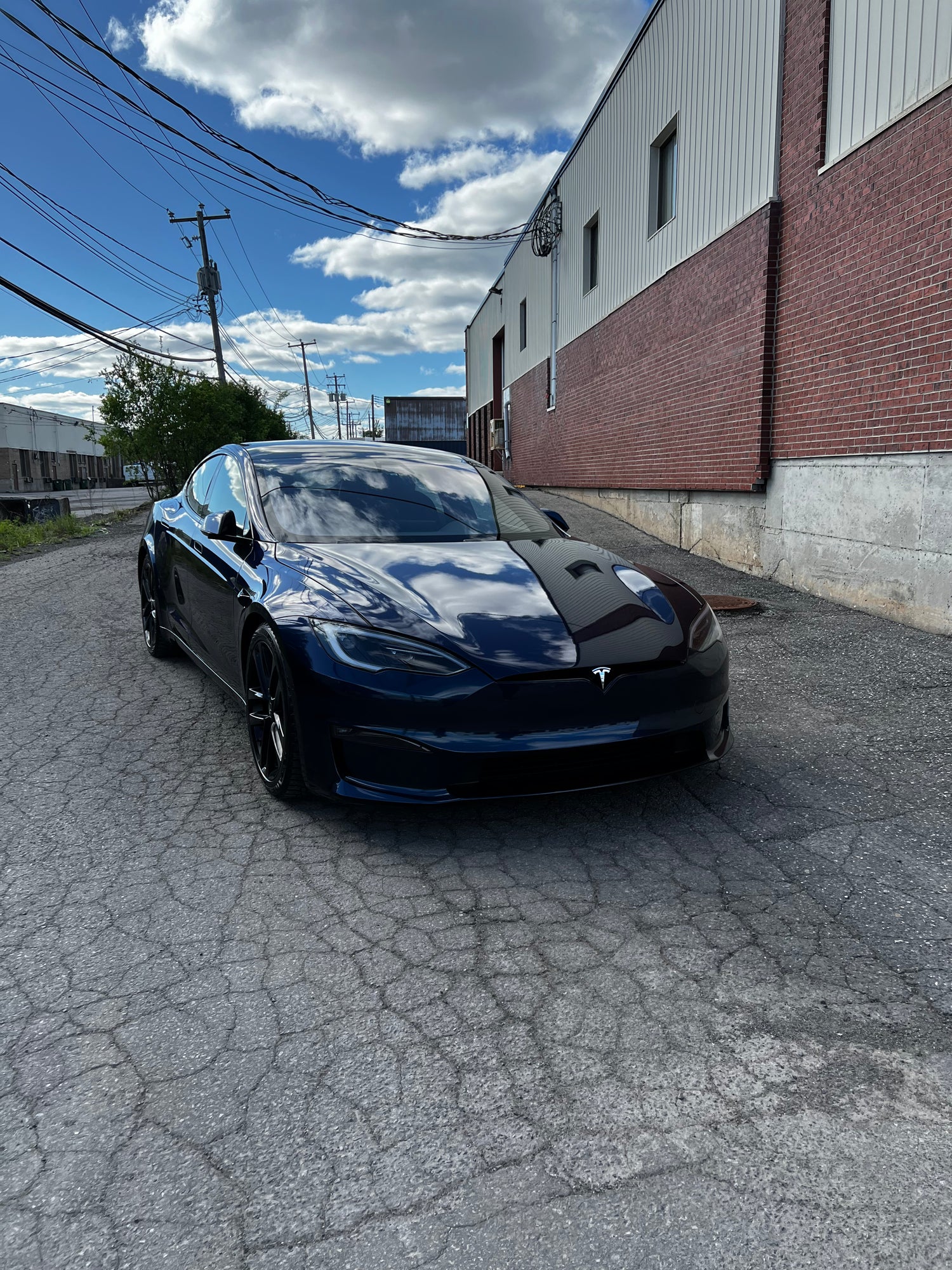 glossy navy blue Tesla Model S with an industrial backdrop
